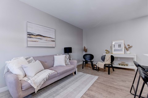 A living room with a grey couch and a painting on the wall.