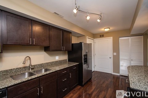 A kitchen with dark brown cabinets and a granite countertop.