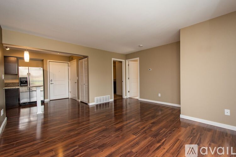 A spacious living room with hardwood floors and a kitchen area in the background.