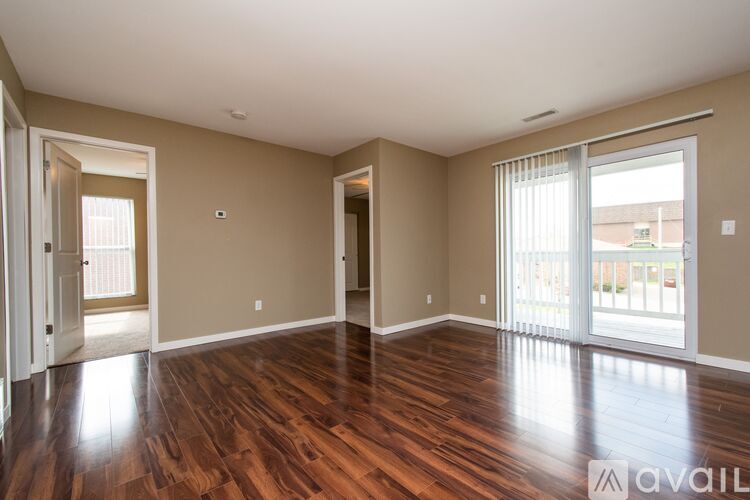 A spacious room with wooden floors and a sliding glass door.