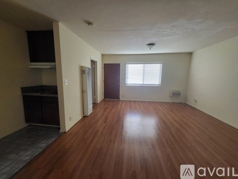 A room with wooden flooring and a window with blinds.