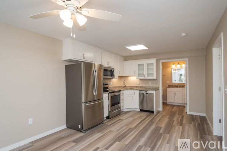 A kitchen with a refrigerator, microwave, oven, and sink.