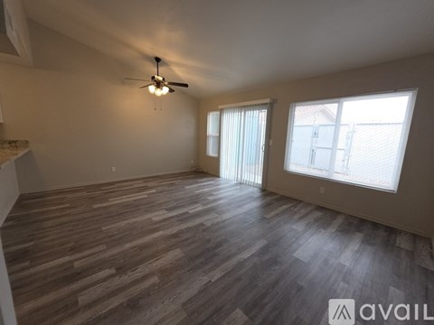 A spacious room with wooden flooring and a ceiling fan.