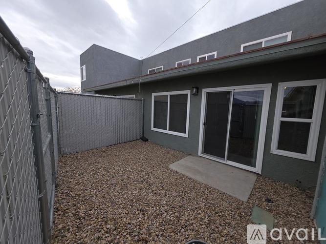 A grey house with a gravel yard and a fence.
