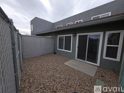 A grey house with a gravel yard and a fence.