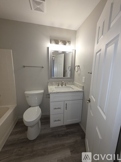 A bathroom with a toilet, sink, and mirror.