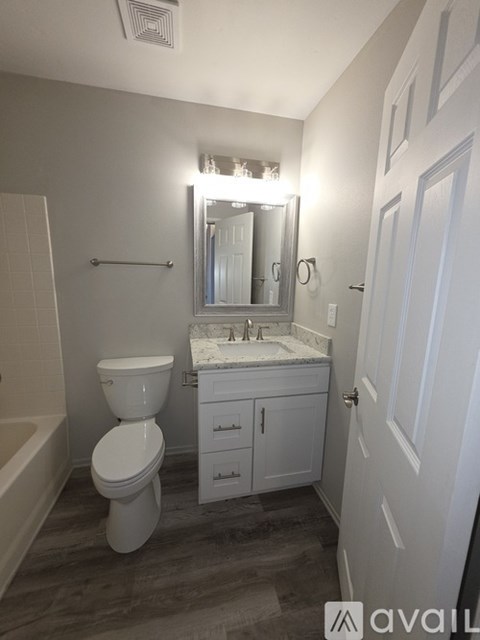 A bathroom with a toilet, sink, and mirror.