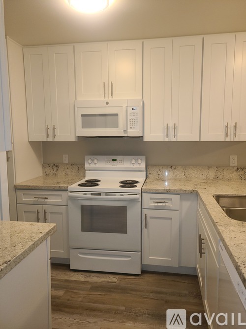 A kitchen with white cabinets and a granite countertop.