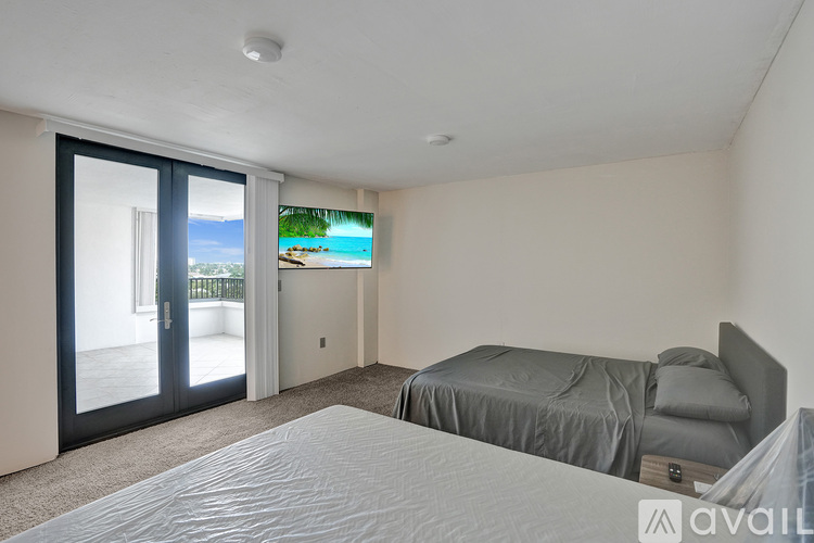 A bedroom with a large bed and a view of the beach through the sliding glass door.