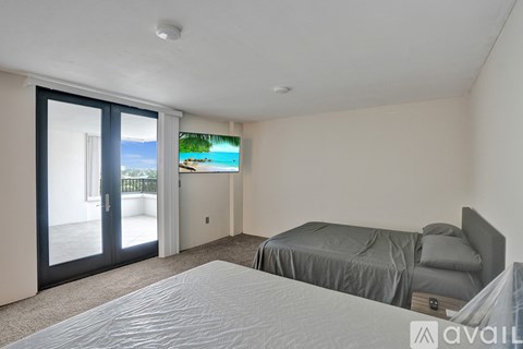A bedroom with a large bed and a view of the beach through the sliding glass door.