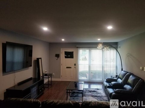 A living room with a black leather couch and a flat screen TV.