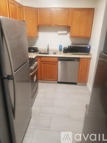 A kitchen with wooden cabinets and a stainless steel refrigerator.