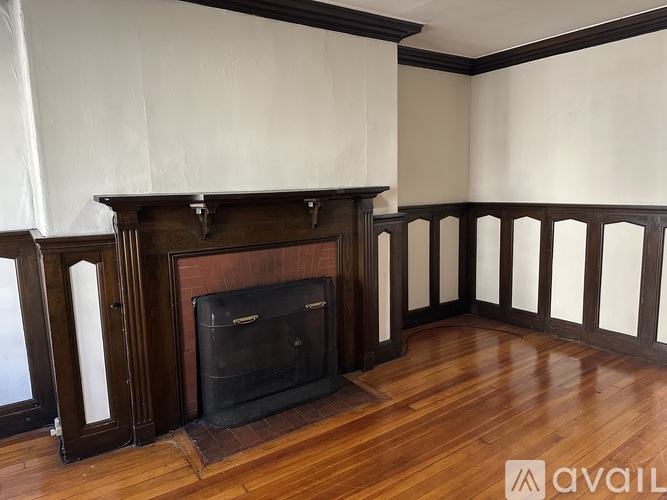 A wood fireplace in a room with wooden floors and white walls.
