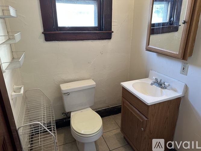 A bathroom with a toilet, sink, and mirror.