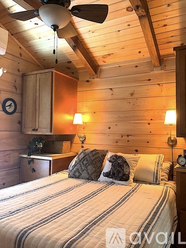 A bedroom with a bed, a ceiling fan, and a clock on the wall.