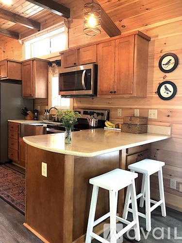 A kitchen with wooden cabinets and a white island with two stools.