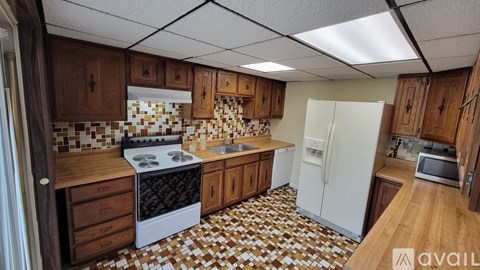 A kitchen with brown cabinets and a white fridge.