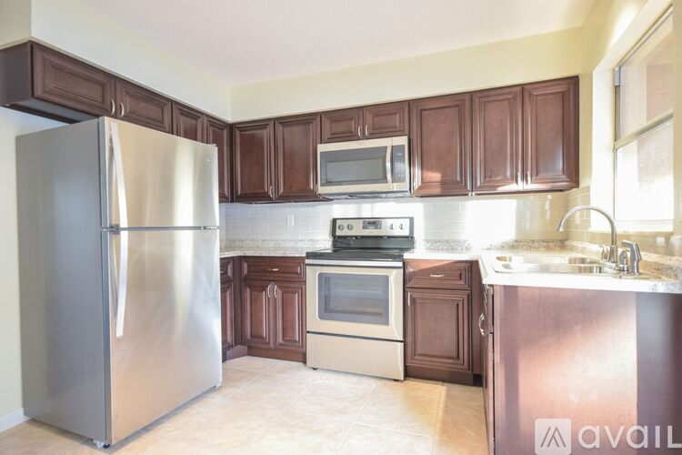 A kitchen with a stainless steel refrigerator, microwave, oven, and sink.