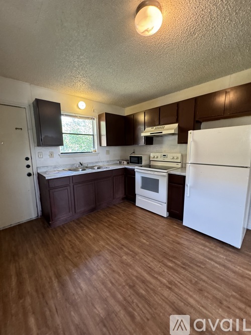 A kitchen with white appliances and brown cabinets.