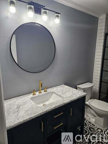 A bathroom with a marble countertop and a round mirror.