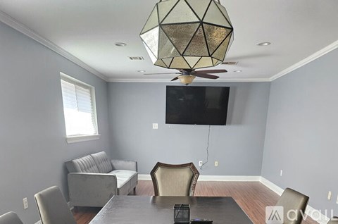 A living room with a grey couch, a black television, and a glass table with a metal base.
