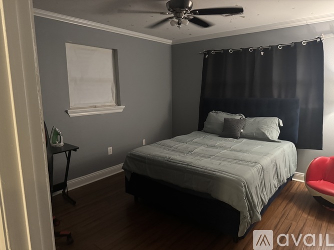 A bedroom with a bed, chair, and ceiling fan.