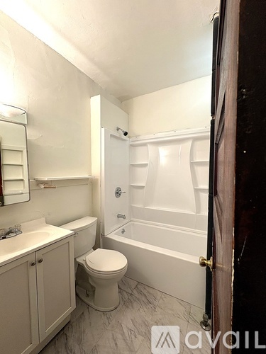 A kitchen with white appliances and a window with a radiator.