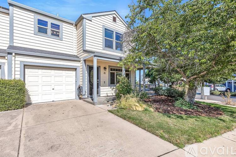 A house with a garage and a tree in front.