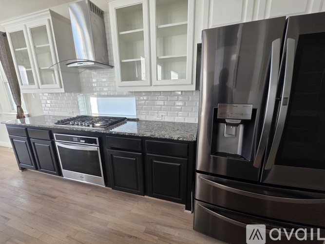 A modern kitchen with a stainless steel refrigerator and black cabinets.