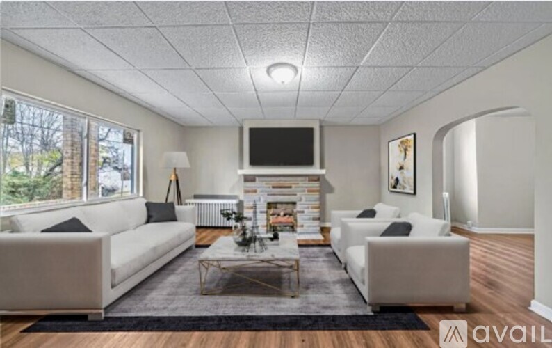 A living room with a white couch, a fireplace, and a television.