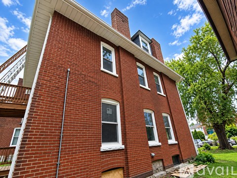 A red brick building with a white window and a chimney.
