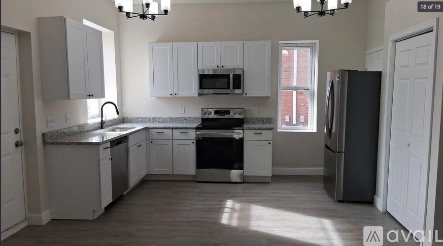 A kitchen with white cabinets and a black fridge.