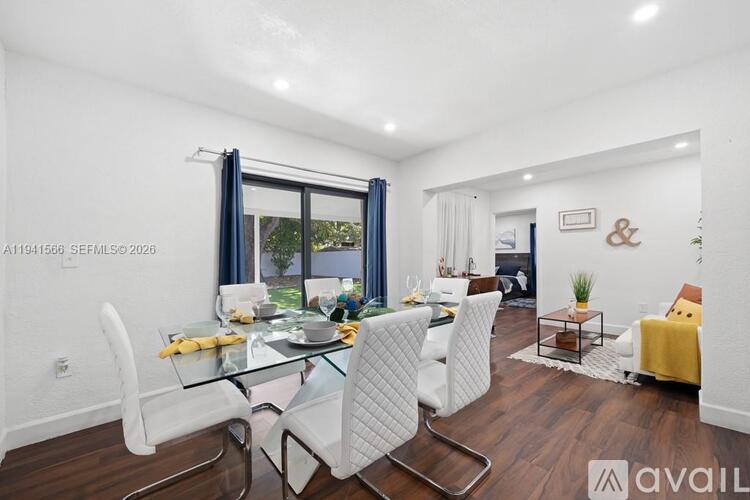 A modern dining room with a glass table and white chairs.