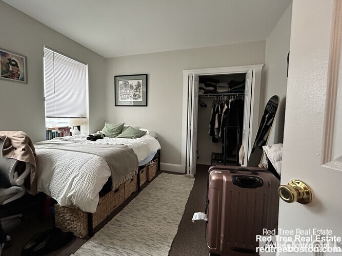 A bedroom with a bed, a suitcase, and a closet.