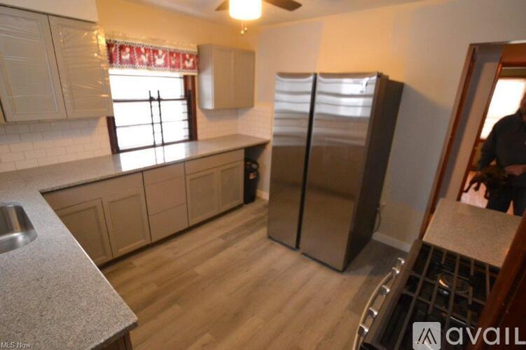 A kitchen with a refrigerator, sink, and cabinets.