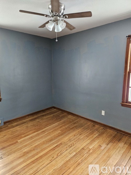 A room with wooden flooring and a ceiling fan.