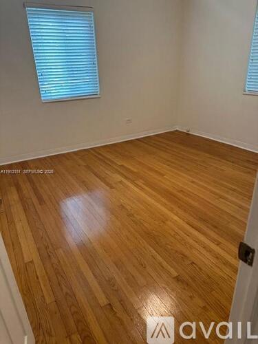 A room with wooden flooring and a window with blinds.