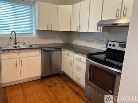 A kitchen with white cabinets and a wooden floor.