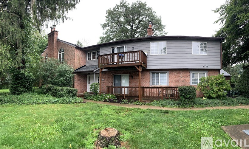A house with a balcony and a tree stump in the yard.