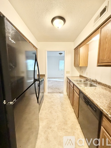 A kitchen with a black fridge and wooden cabinets.
