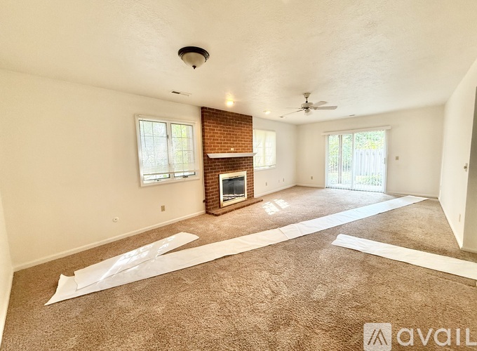 A living room with a fireplace and a carpet on the floor.