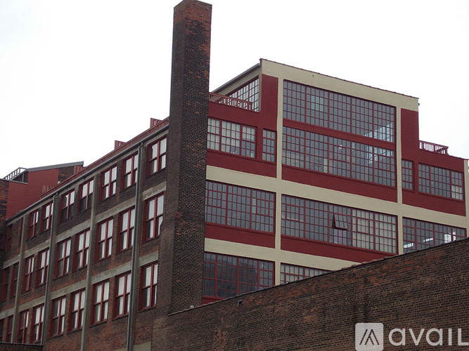 A tall building with a brick chimney and a sign that says "AVAIL" on the side.