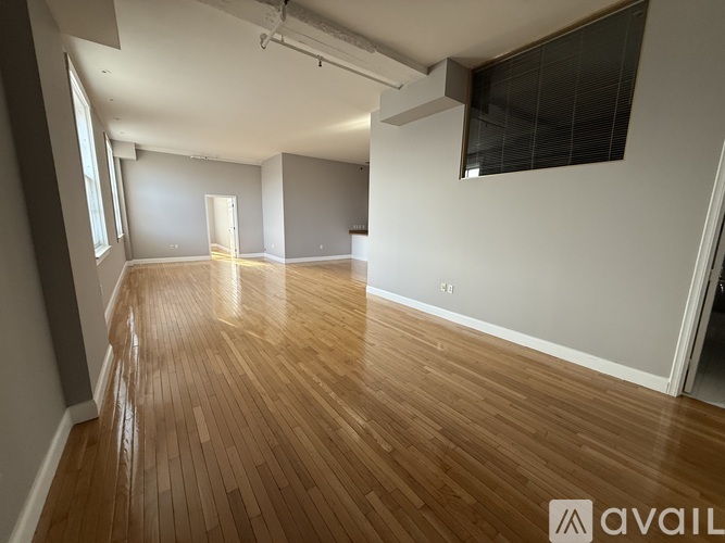 A spacious room with wooden flooring and white walls.