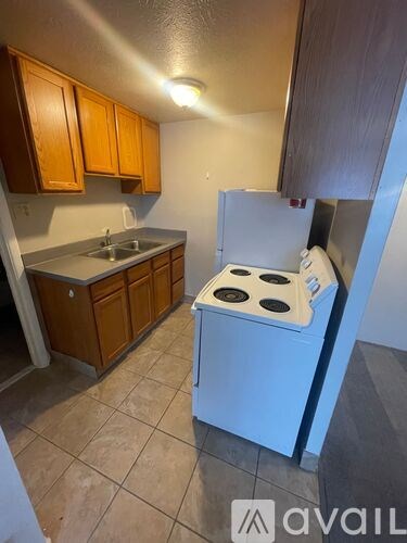 A kitchen with a white stove and wooden cabinets.