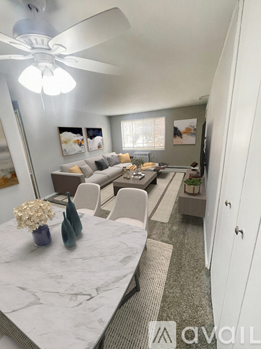 A living room with a couch, chairs, and a dining table.