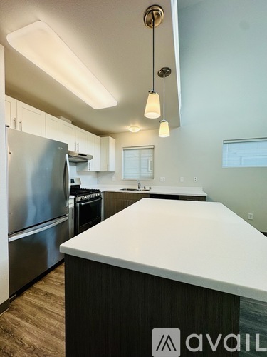A kitchen with a white counter top and a stainless steel refrigerator.