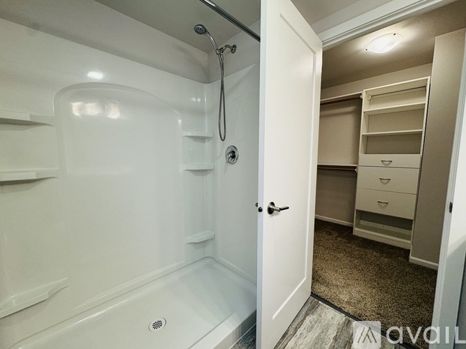 A white bathroom with a walk-in shower and a white door leading to a bedroom.