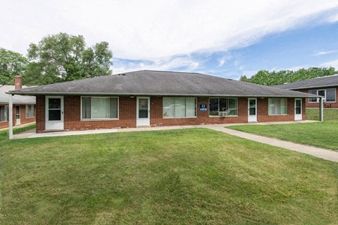 the front of a brick house with a grassy yard