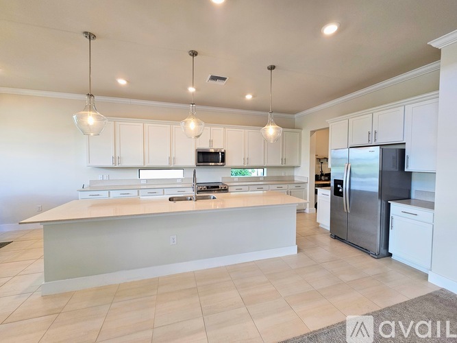 A kitchen with white cabinets and a large island in the middle.