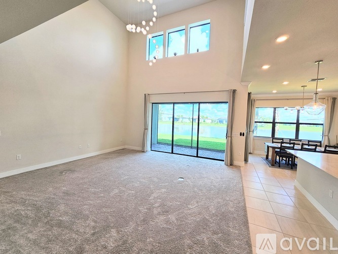 A spacious living room with a carpeted floor and a dining area with a table and chairs.